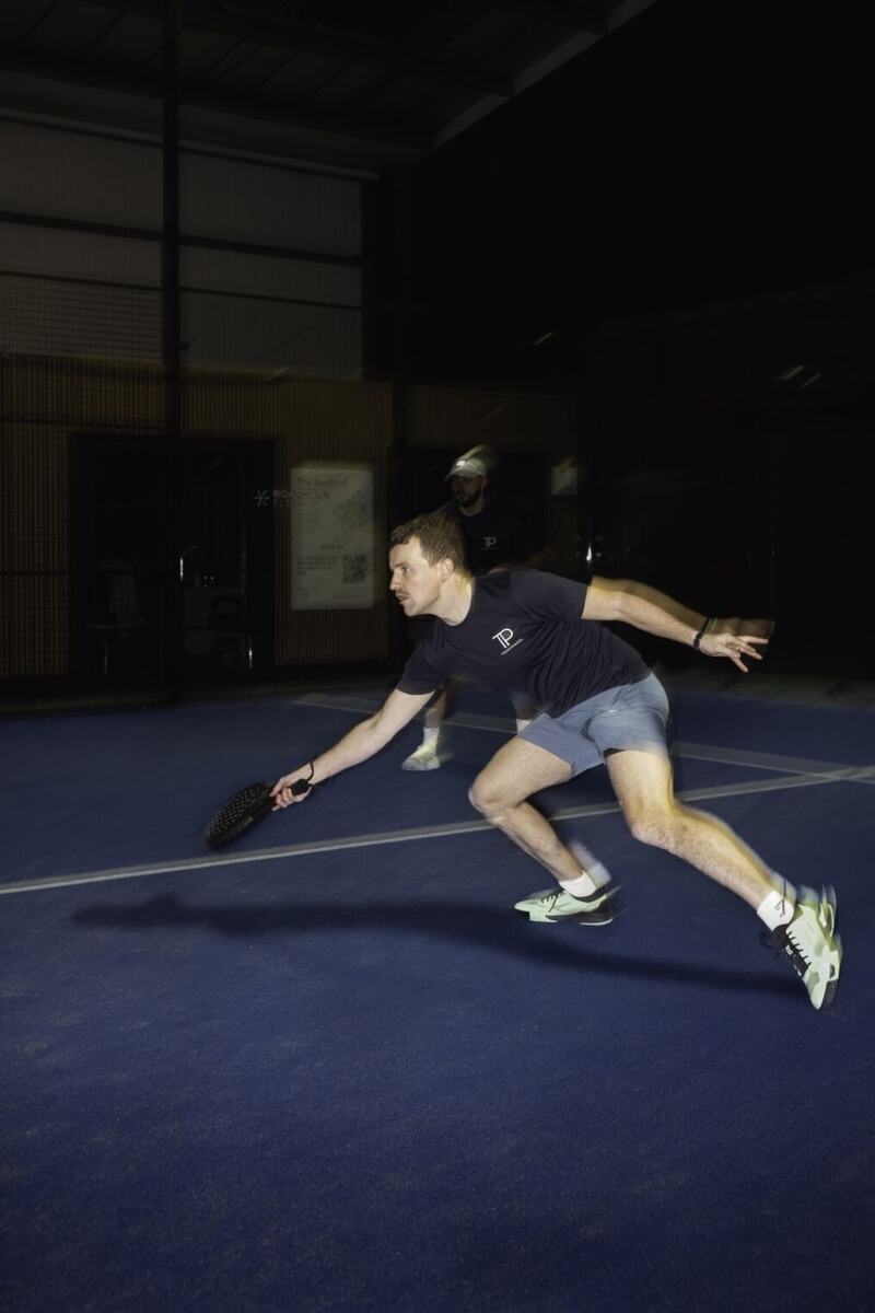 A player lunging low for a shot on a blue indoor court.
