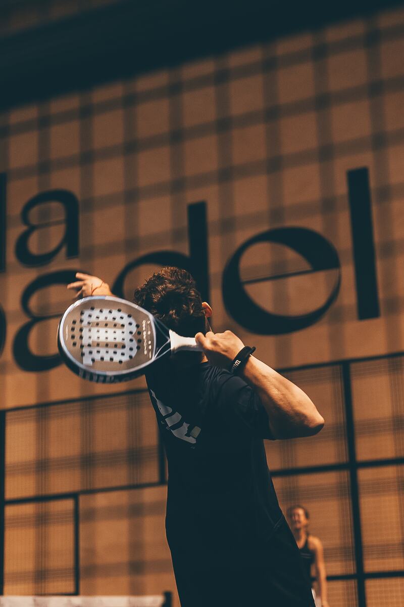 A player winding up for a shot in front of a large Vida Del Padel sign.