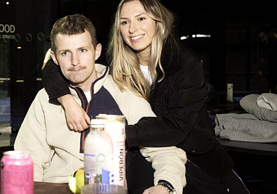 Two friends smiling together at a table at a padel club.