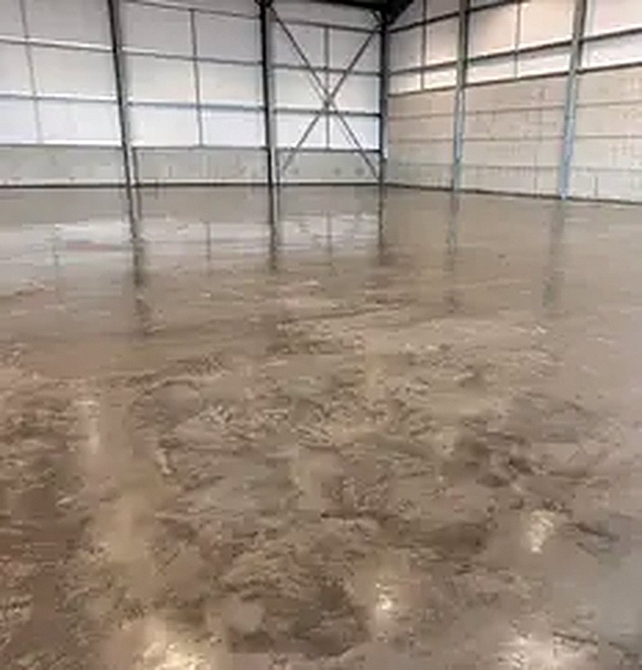 A large, level, polished concrete floor inside a big shed with pale walls and steel columns.
