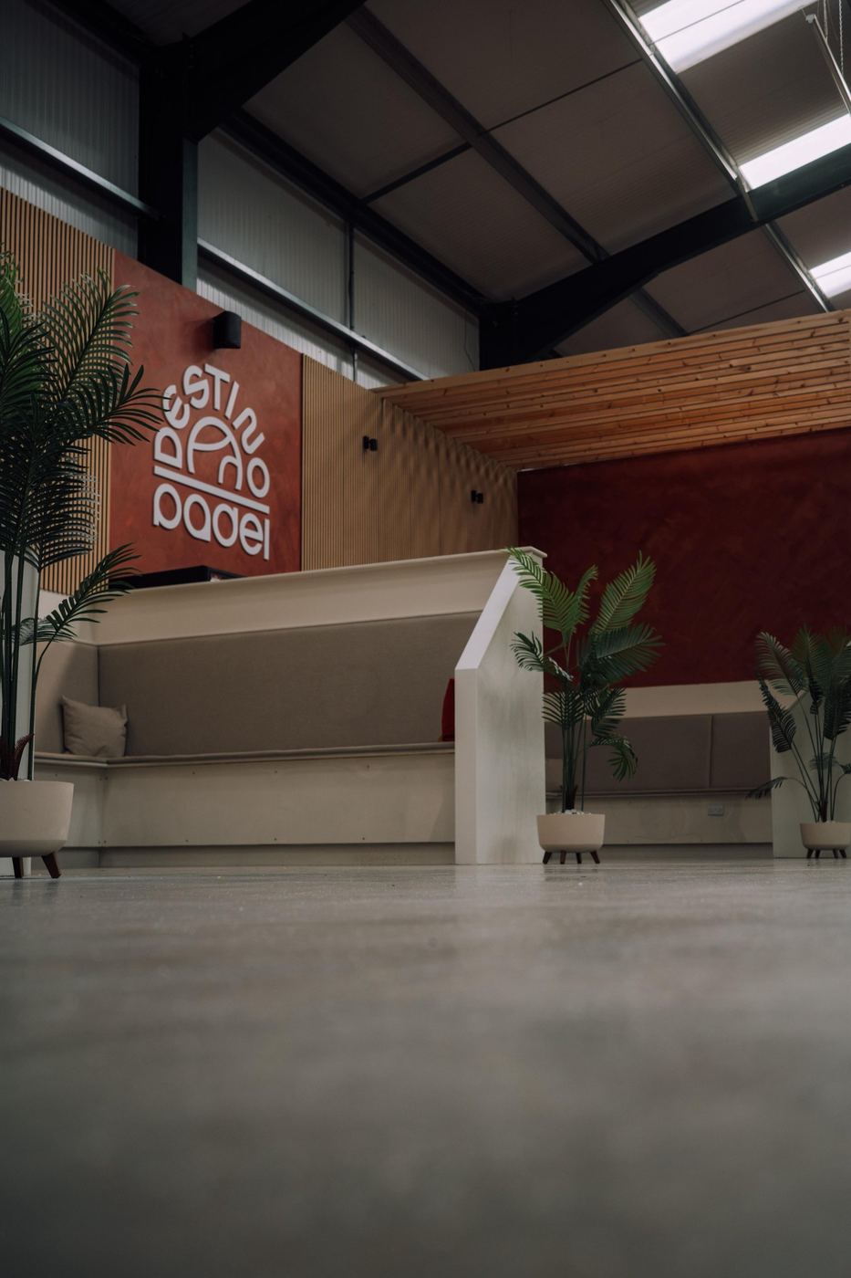 The reception area with a terracotta feature wall, a pale desk and house plants