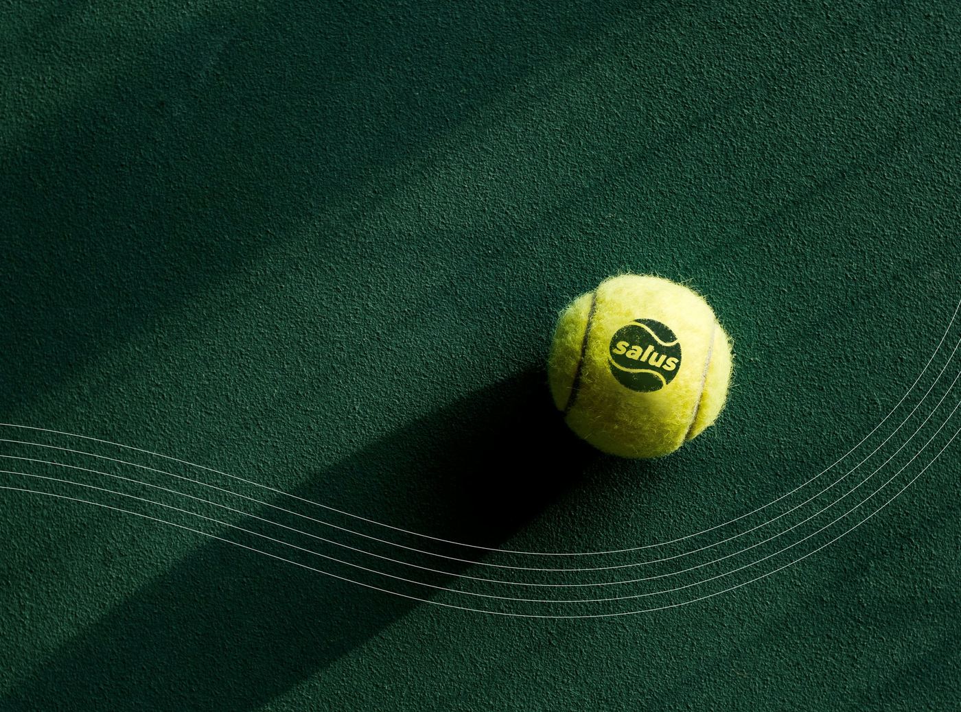 A yellow padel ball with the Salus logo resting on dark green turf
