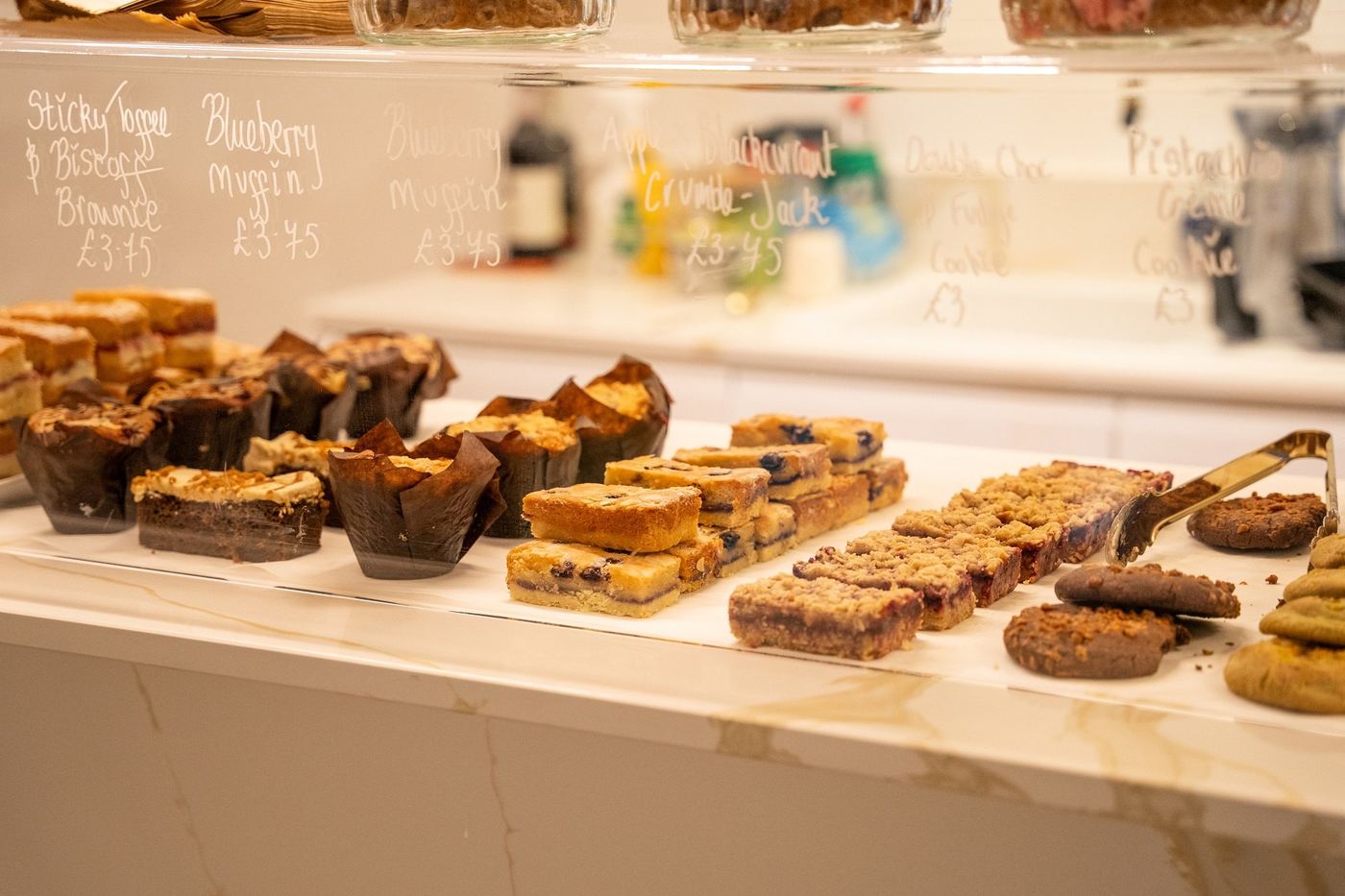 Cakes and traybakes on the counter of the club cafe, with a chalkboard menu behind