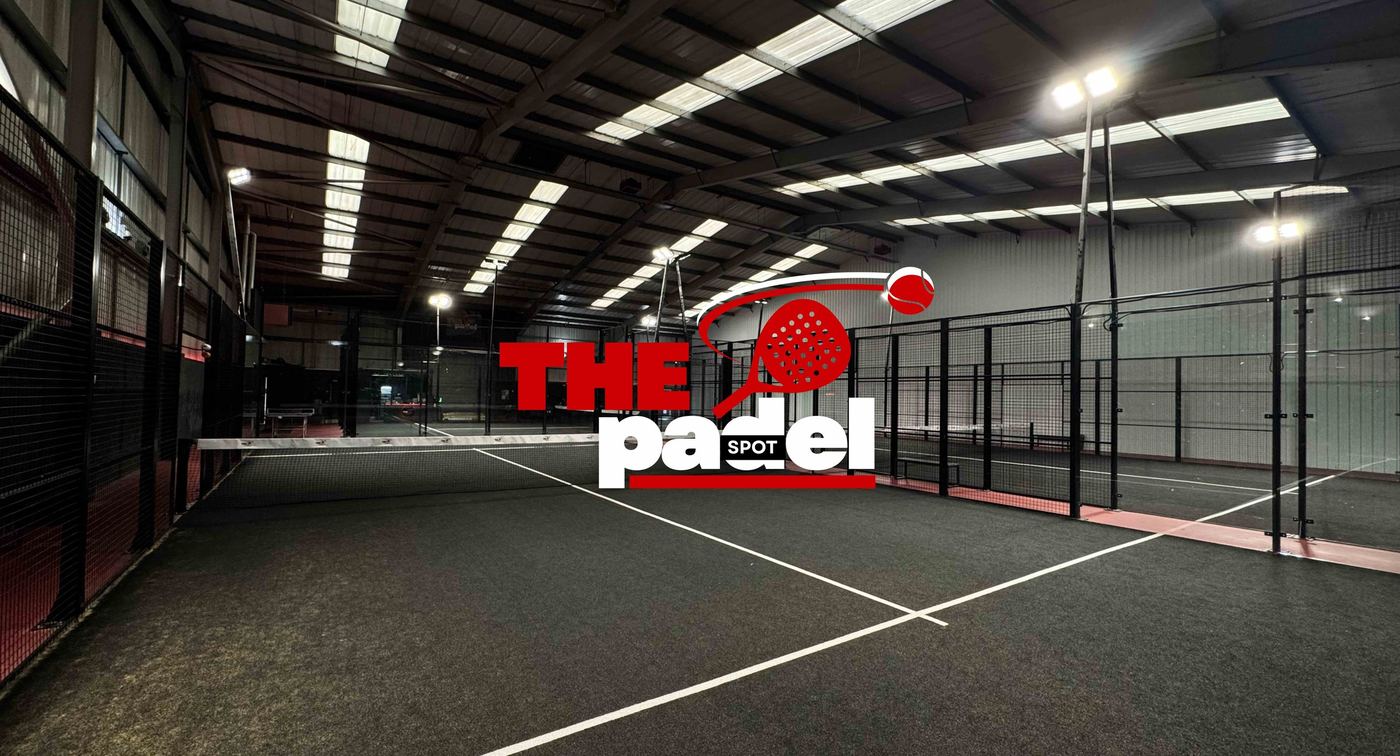 A wide view of the indoor hall with black padel courts and the Padel Spot logo