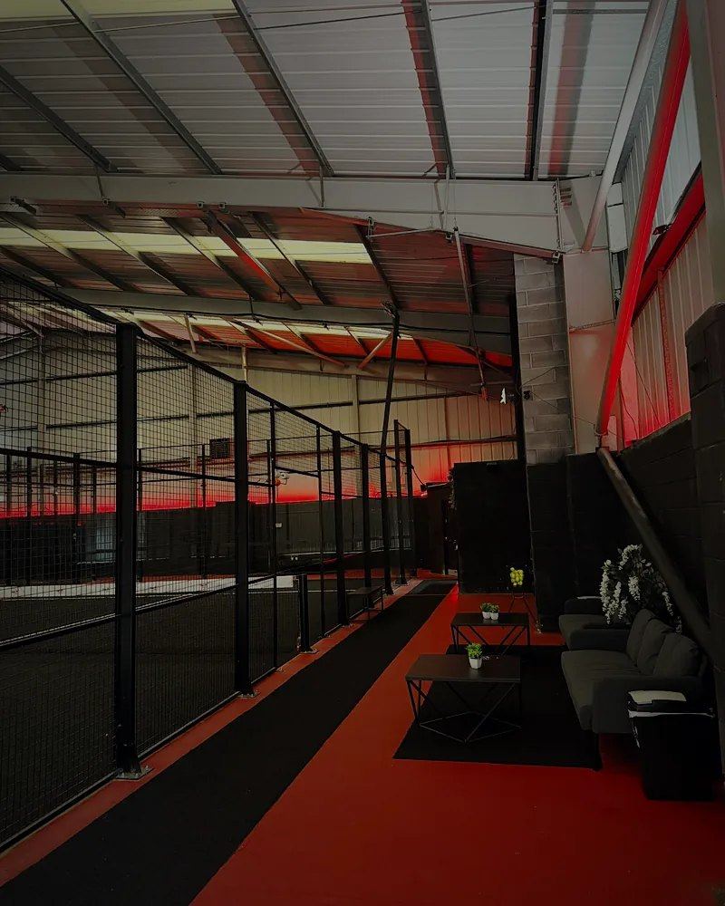 A lounge with sofas beside the courts, with red lighting and a red floor strip
