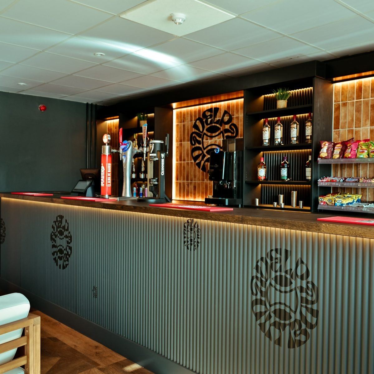 A club bar with draught taps, a shelf of bottles and a ribbed front panel carrying the club emblem